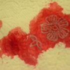 A pale yellow tissue embossed with a paisley design that has stains of red food coloring resembling blood in the center. The largest stain has a small, five-petaled flower sketched on top in a gold ink.