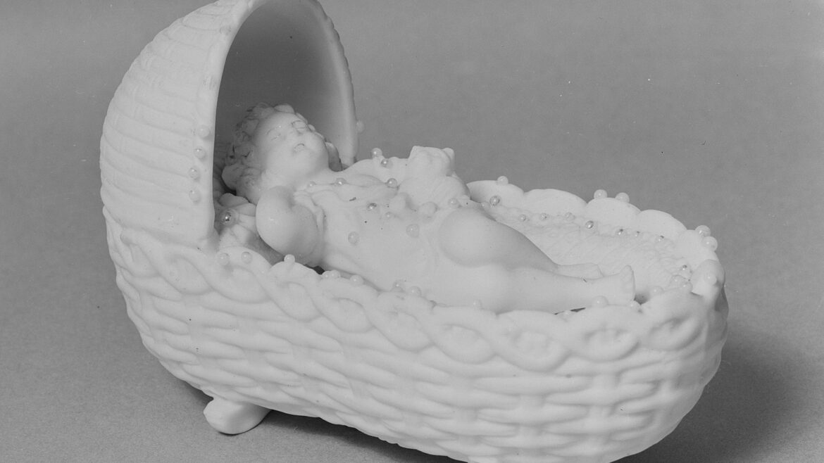 All white photograph of marble statue of a baby in a cradle.