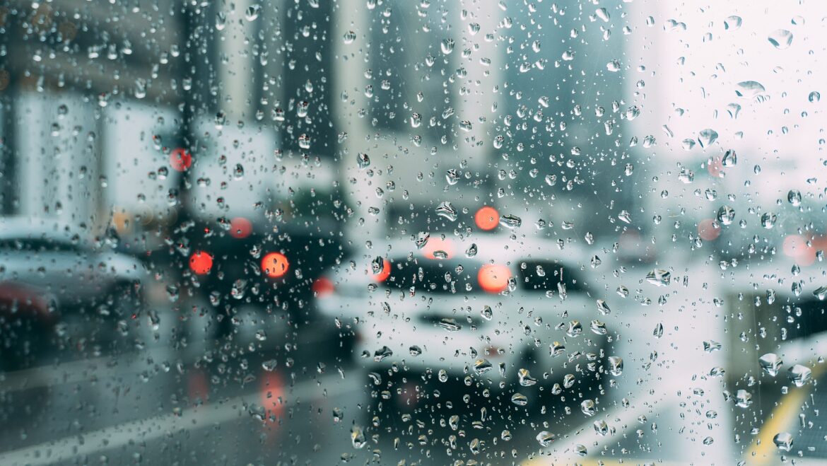 This is a photograph of a busy city street thorugh a rain-streaked piece of glass.